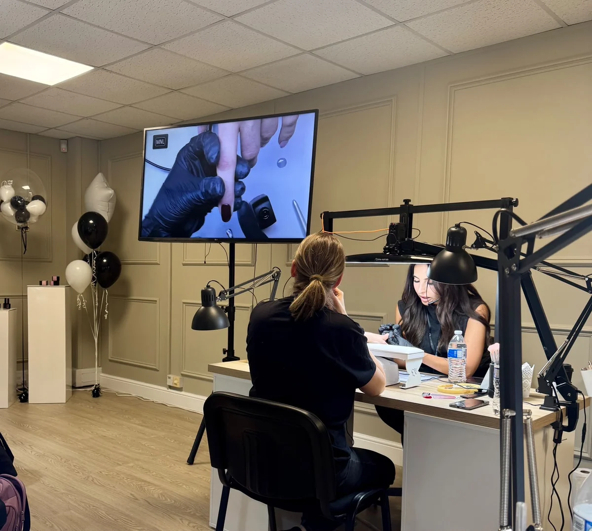 Natalia teaching at a live nail event, with her technique displayed on a large screen